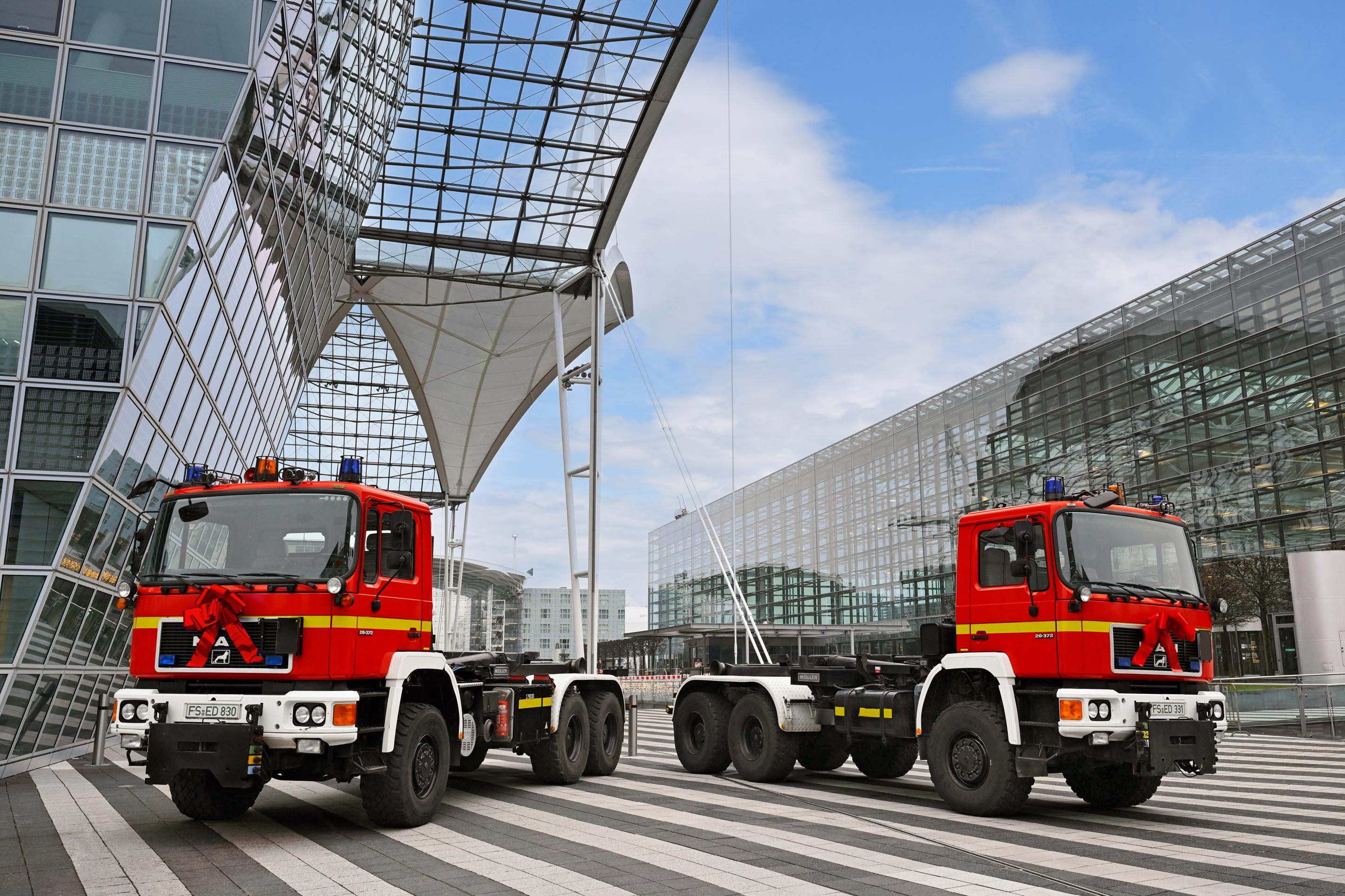 Die Flughafenfeuerwehr übergab je ein Wechselladerfahrzeug an das Technische Hilfswerk Freising und den Kreisfeuerwehrverband Erding.